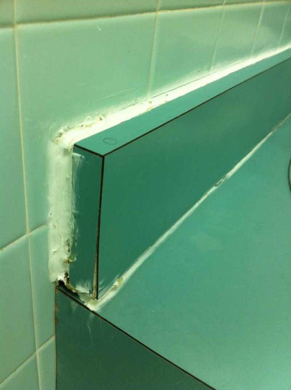 Thick, uneven caulk smeared around the edge of a tiled fixture