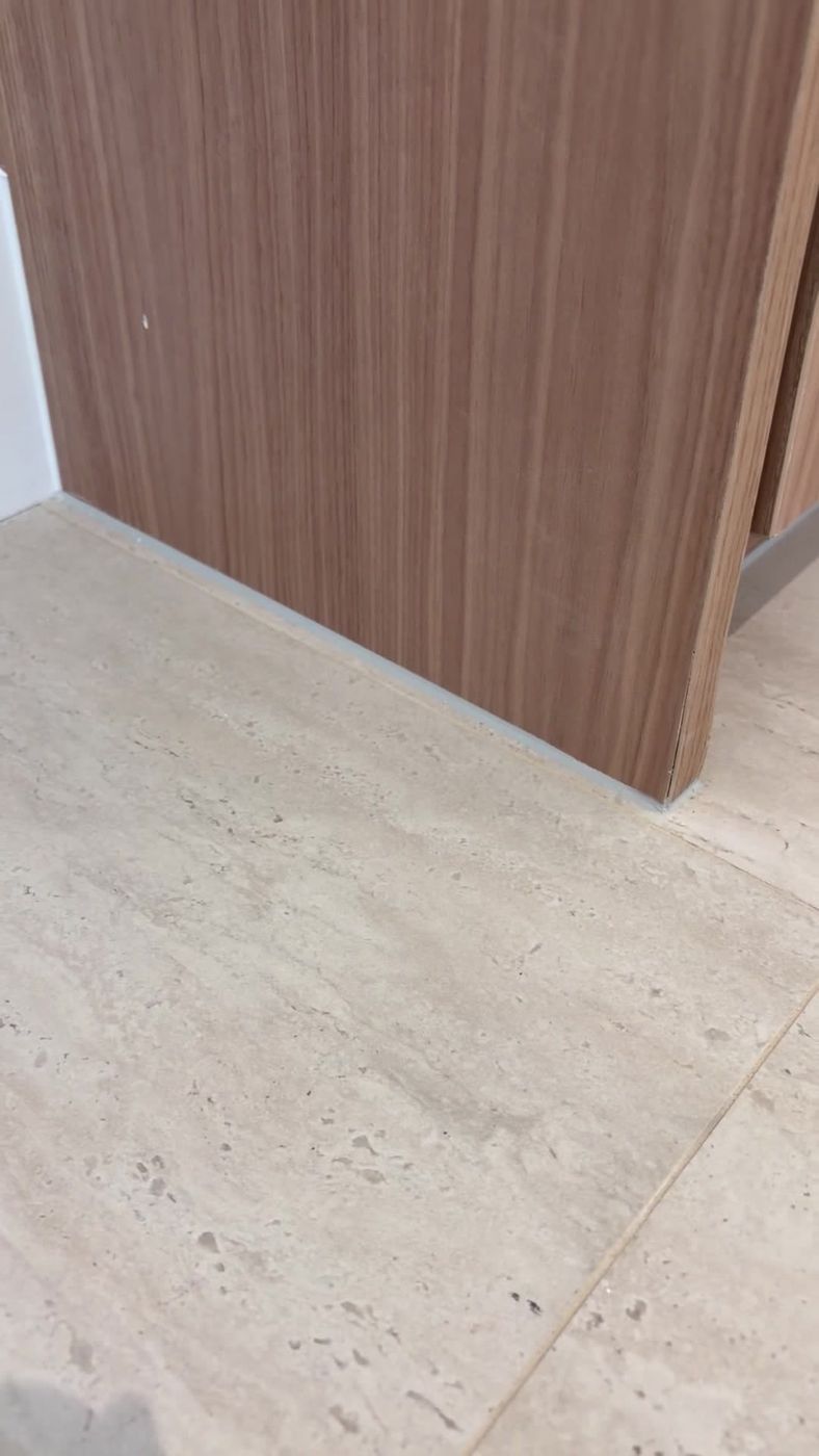 Detailed floor-line seal around a wood cabinet corner